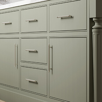 Slab inset cabinet doors with a beaded frame in a light sage green paint color.