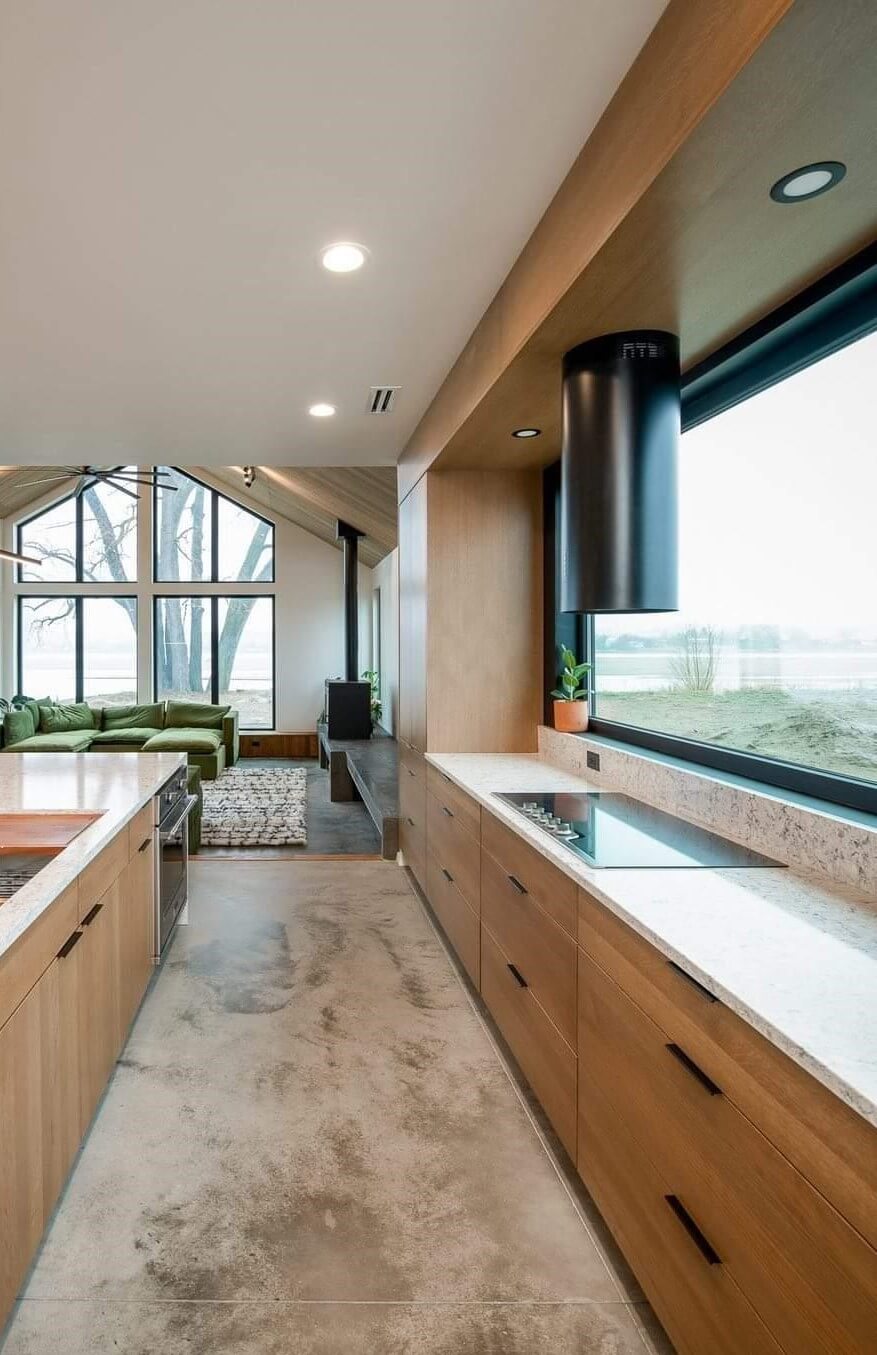 A contemporary kitchen with warm white oak cabinets with slab cabinet doors and black window frames and architectural accents.