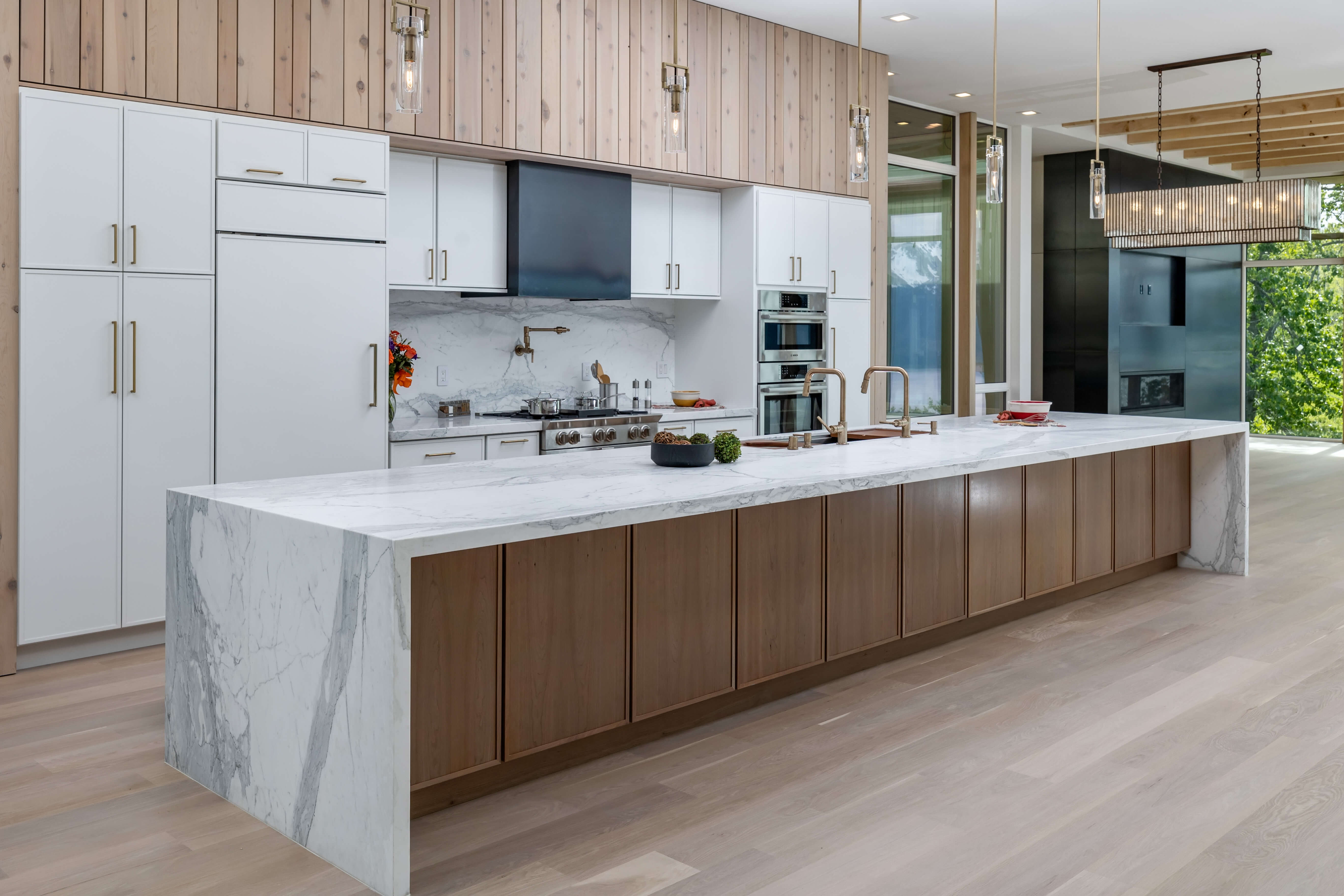 A warm and trendy kitchen design with a long kitchen island and paneled soffets above the cabinets.