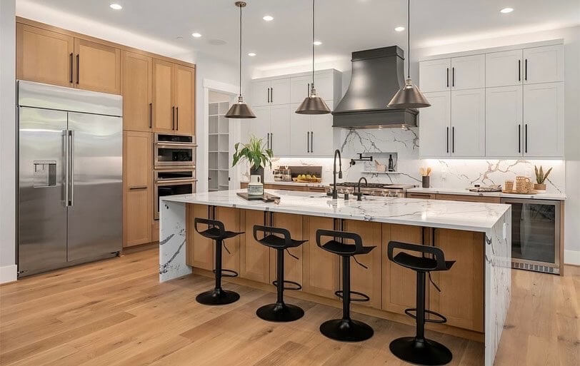 A modern kitchen with white painted cabinets and light stained Qtr. Sawn White Oak accent cabinets and kitchen island with a waterfall countertop.