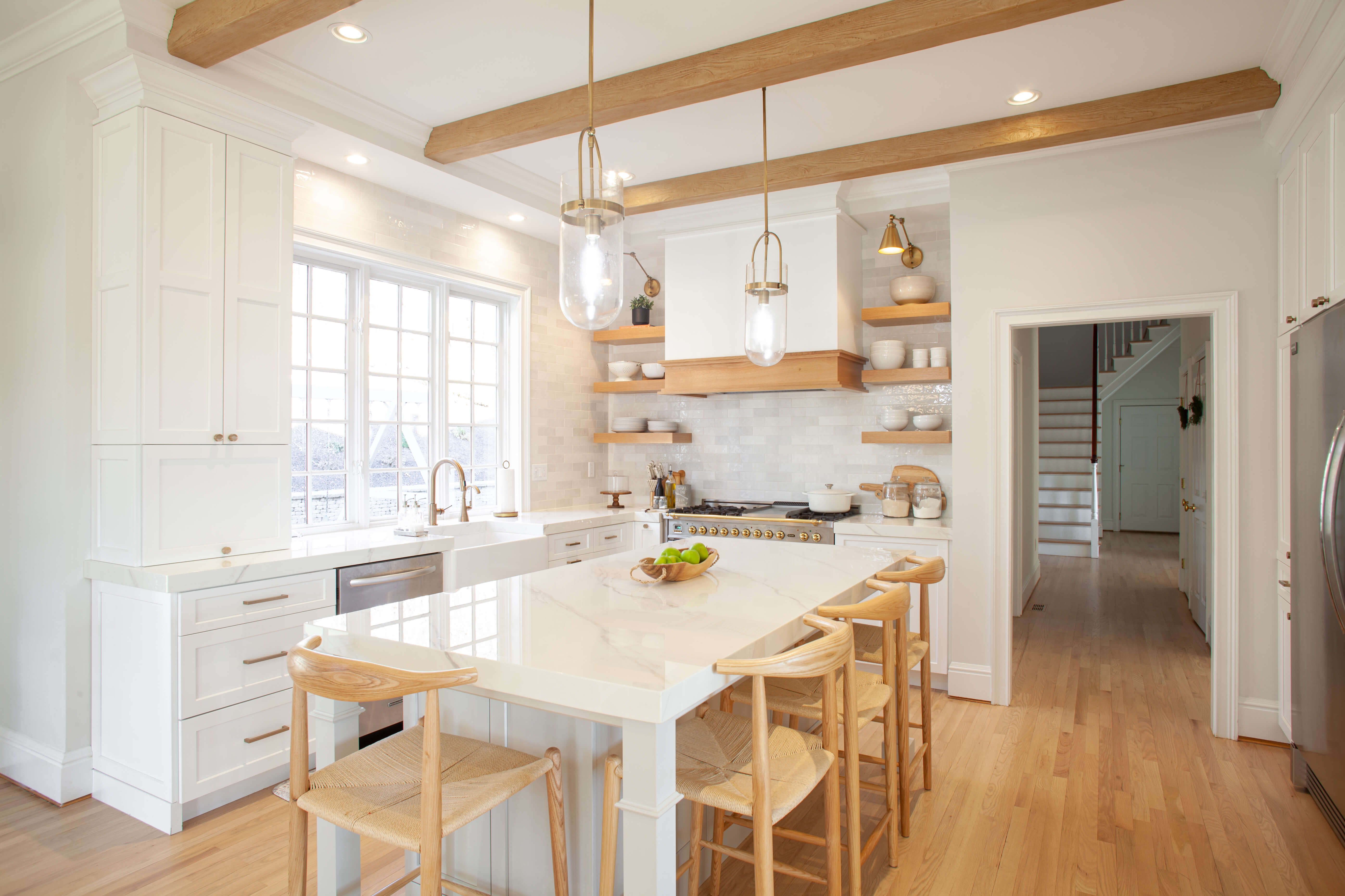 A beautiful kitchen remodel with all-white painted cabinets and light stained oak wood accents.