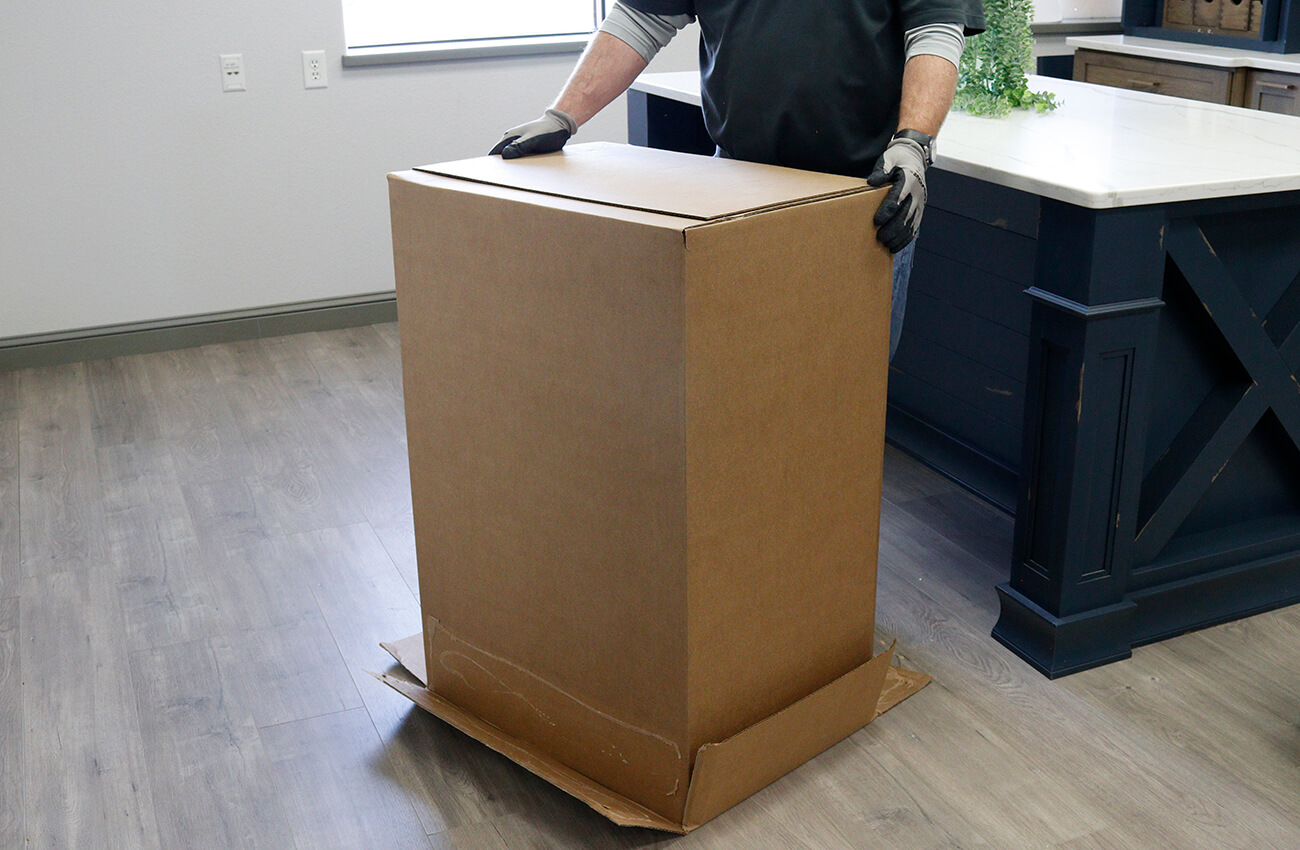A cabinet installer opening a cabinet in a carton box without using a cutting tool.