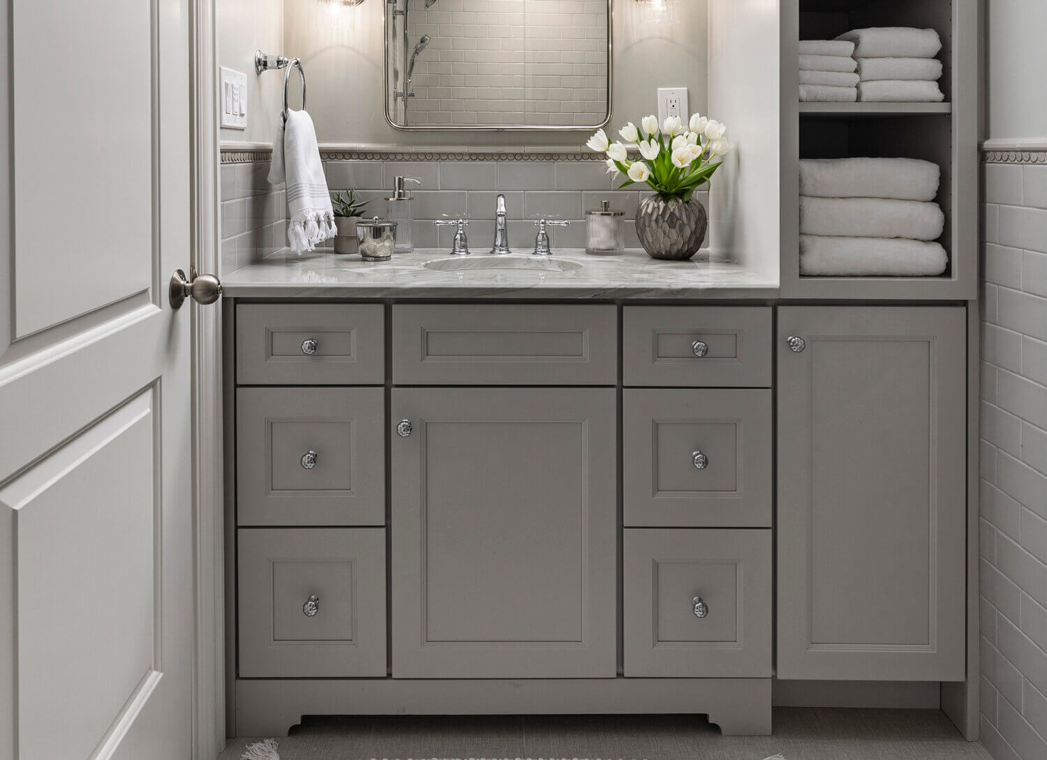 All gray bathroom design with a small gray vanity with a tall and thin tower on thr right side of the sink.