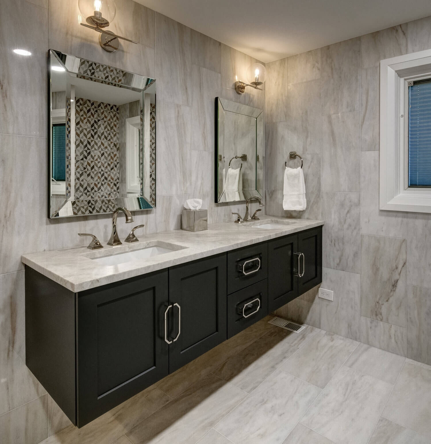 A black painted floating bathroom vanity with two sinks in a transitional styled bathroom.