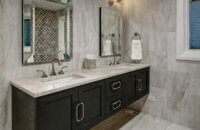 A black painted floating bathroom vanity with two sinks in a transitional styled bathroom.