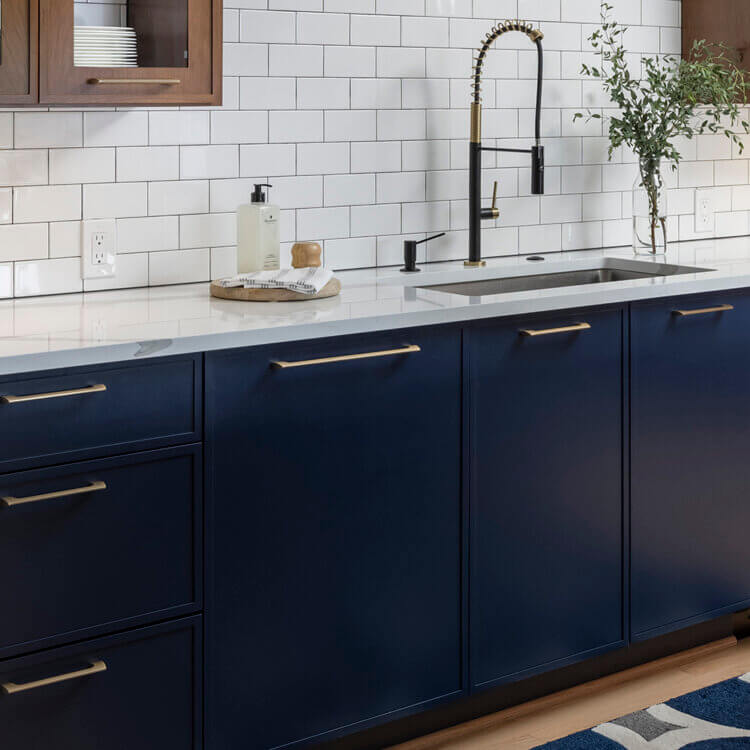 A modern kitchen with skinny shaker cabinet doors in a navy blue paint and a warm stained cherry wood.