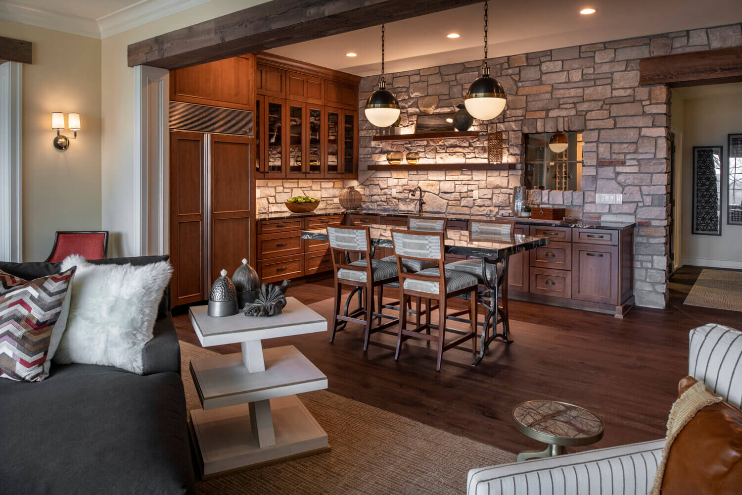 A traditional and rustic home bar and wet bar area with warm stained cherry cabinets and a stone accent wall.