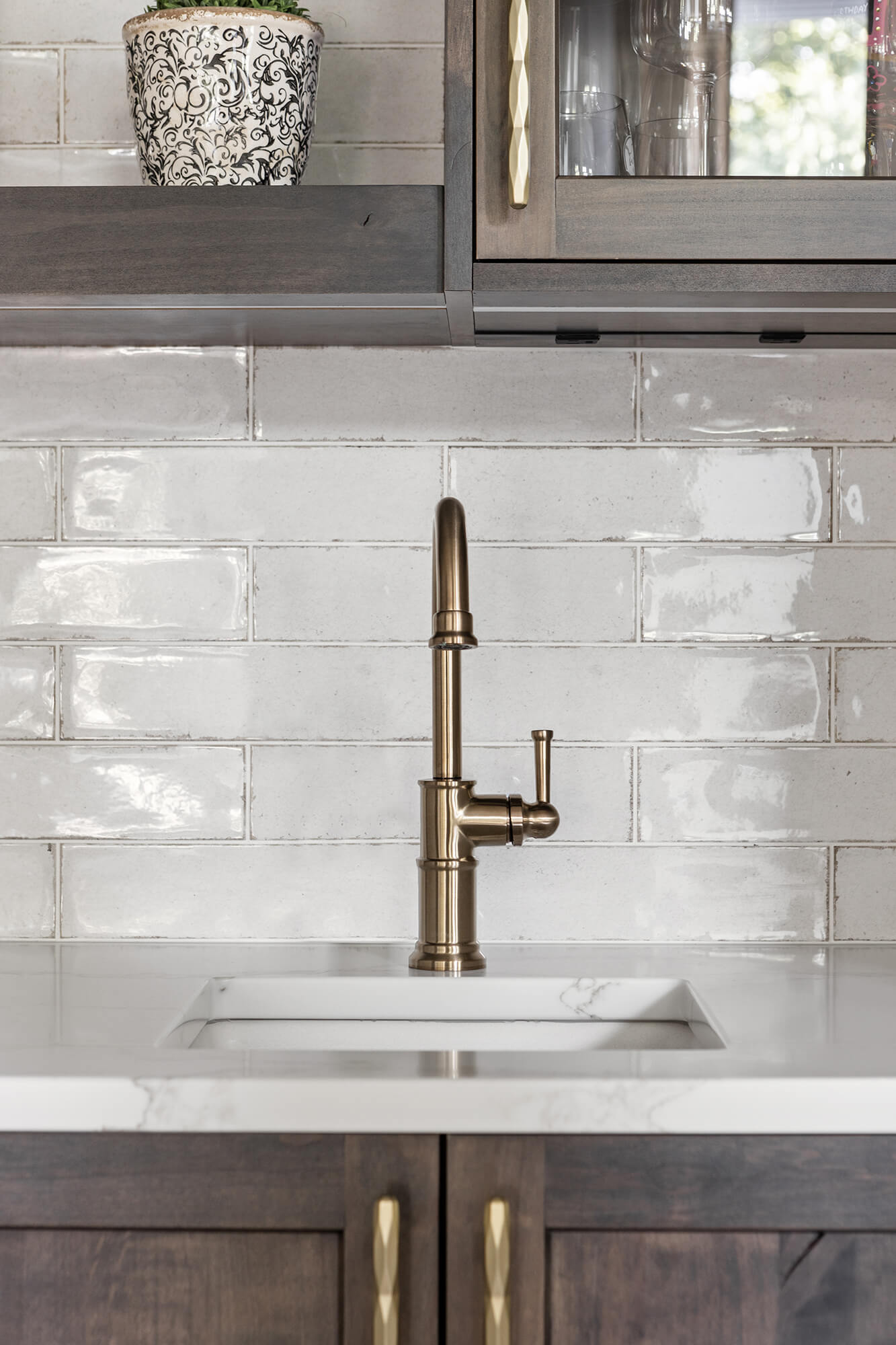 A brushed brass faucet and cabinet hardware goes beautifully with the dark stained kitchen cabinets.