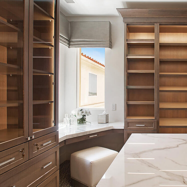 A beautiful walk-in closet design with custom cabinets and a vanity desk.