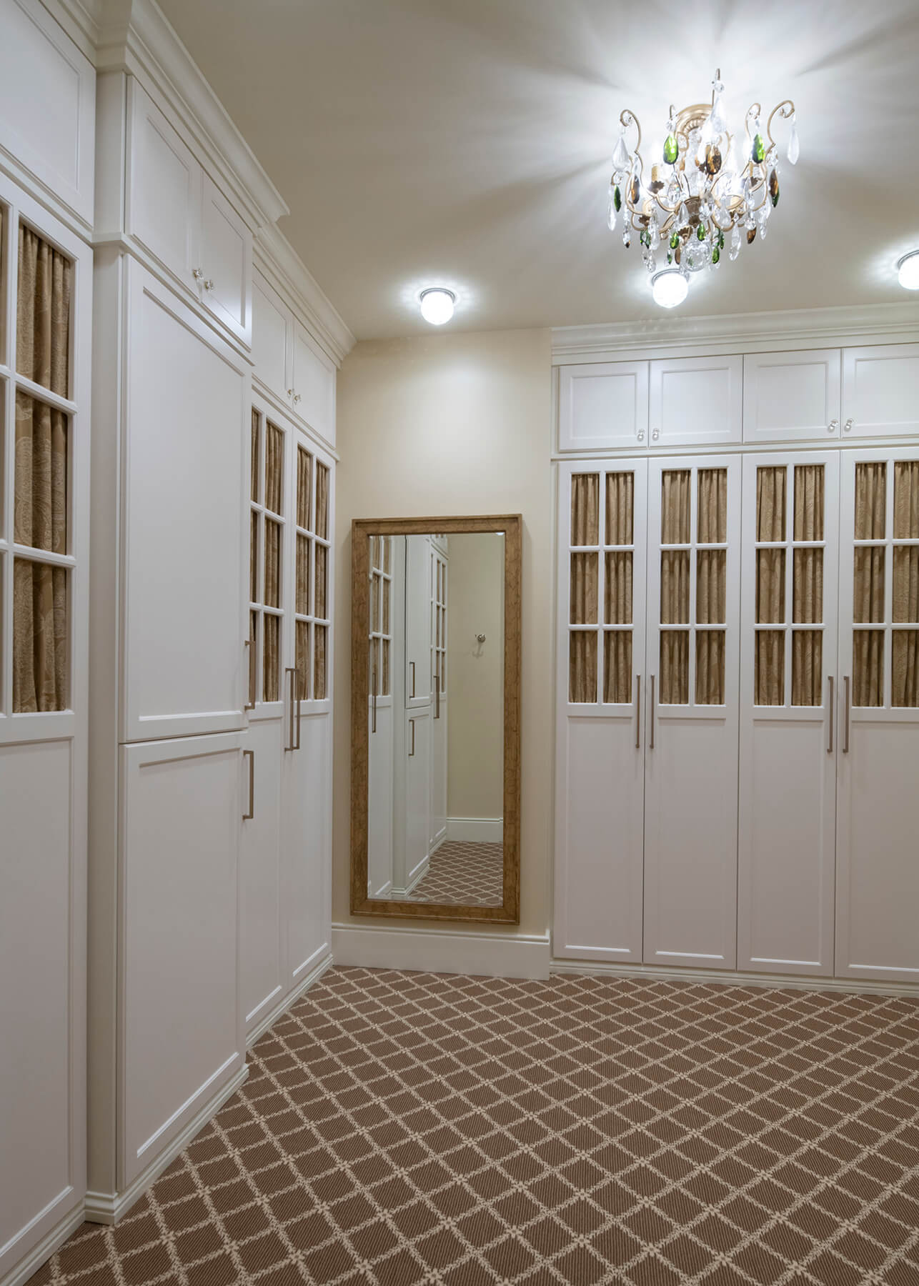 A walk-in closet with mullion cabinet doors that use a curtain for the insert as an accent and way to make the storage breathable.