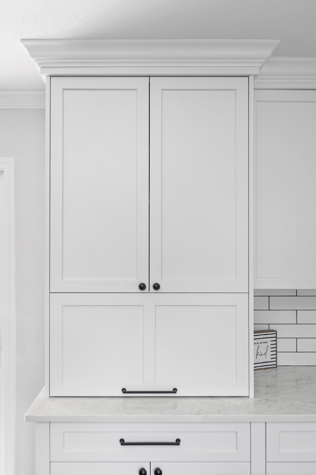 A larder cabinet with a lift-up cabinet door that hides several powered appliances at countertop level. Shown closed.