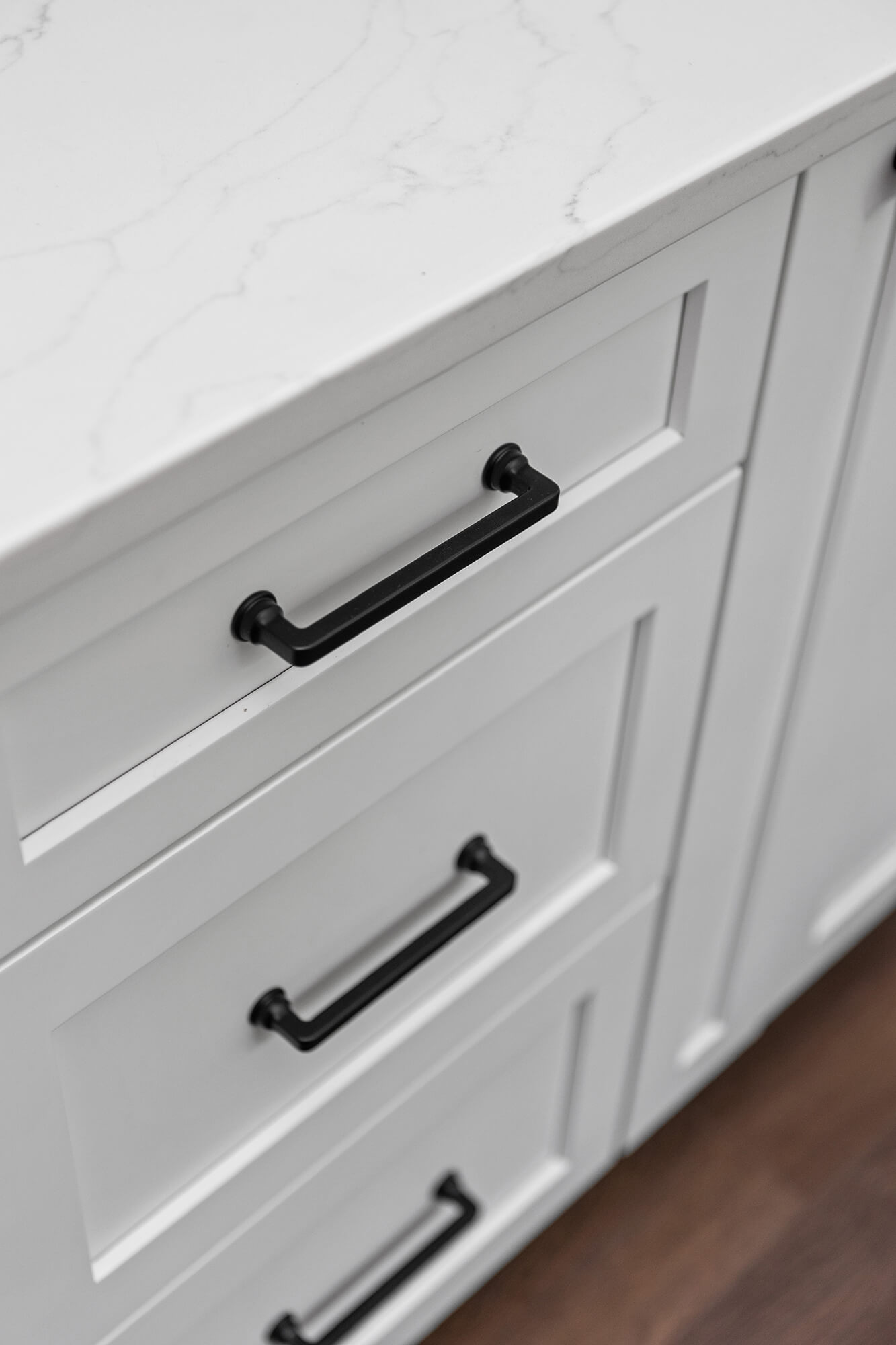 White painted shaker cabinets with black pulls.