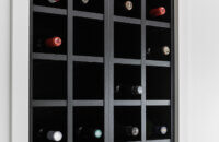 A close up of the black stained wall wine rack cabinet surrounded by bright white cabinets.