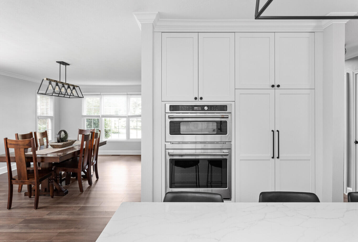 A view toward the dining room from the kitchen in a bright white kitchen design.