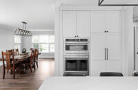 A view toward the dining room from the kitchen in a bright white kitchen design.