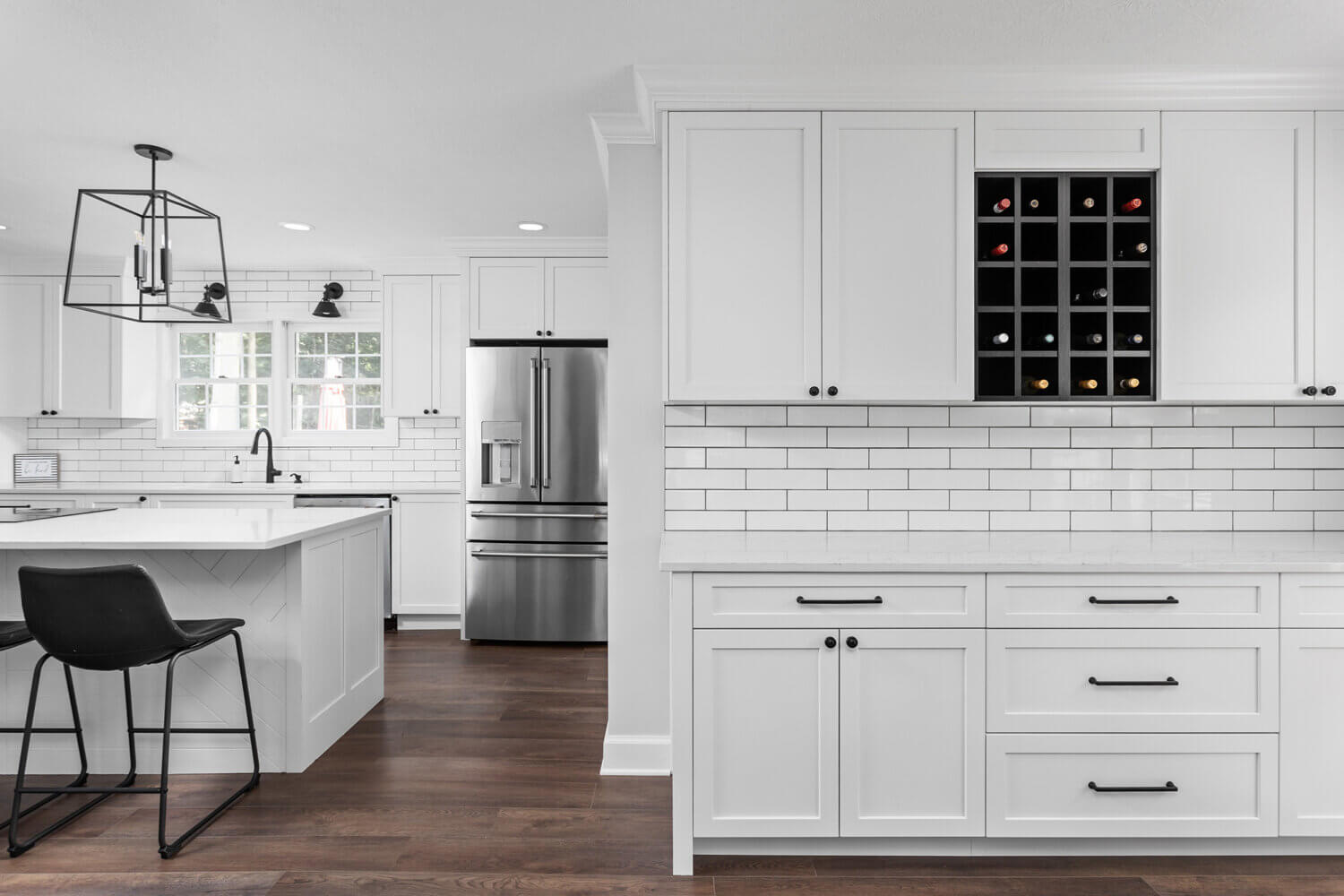 A bright, all-white kitchen with black accents including a black wine rack in a wall cabinet.