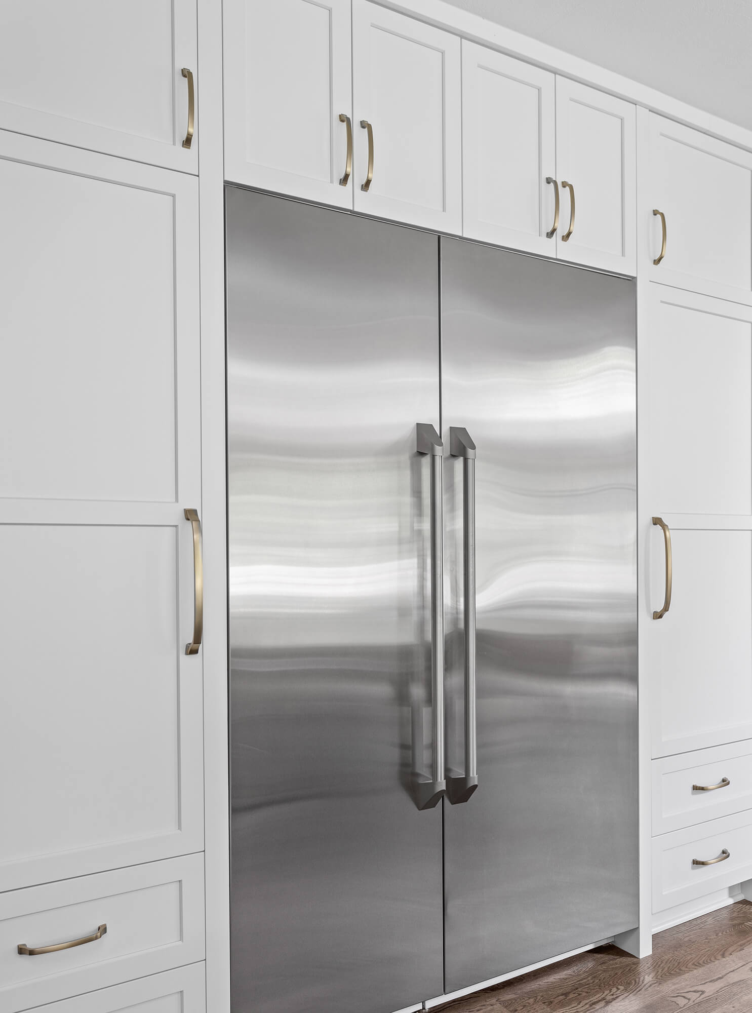 The fridge wall has floor to ceiling cabinets with a white painted finish and shaker doors.
