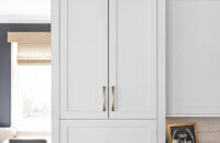 A closed white painted cabinet sitting at countertop height that hides several kitchen appliances behind closed doors. Shown here in the closed position.
