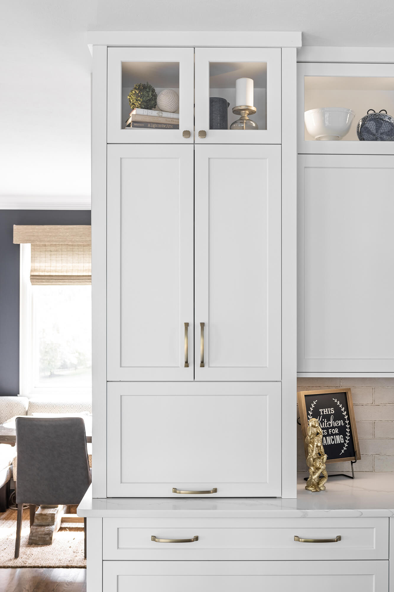 A closed white painted cabinet sitting at countertop height that hides several kitchen appliances behind closed doors. Shown here in the closed position.