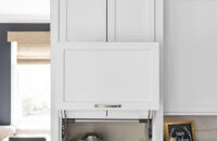 A closed white painted cabinet sitting at countertop height that hides several kitchen appliances behind closed doors. Shown here in the open position revealing the coffee center.