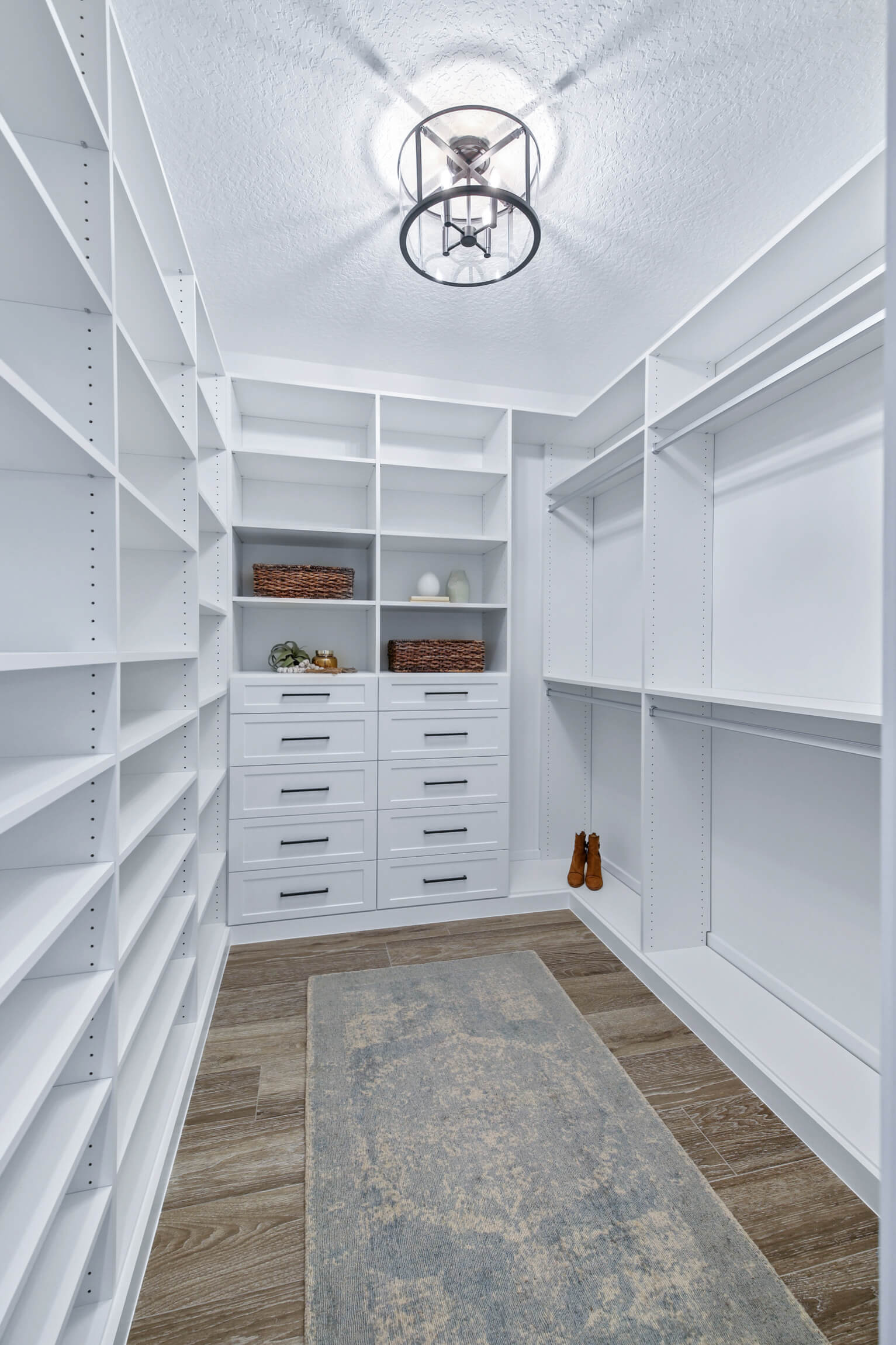 A bright white walk in closet with drawers and shelves.