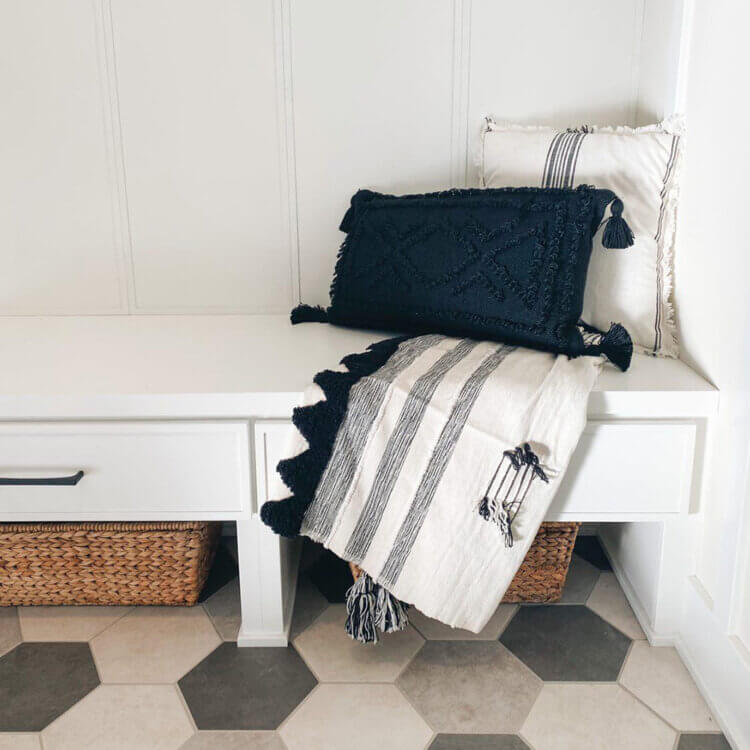 A bright white boot bench with drawers and space under for basket storage.