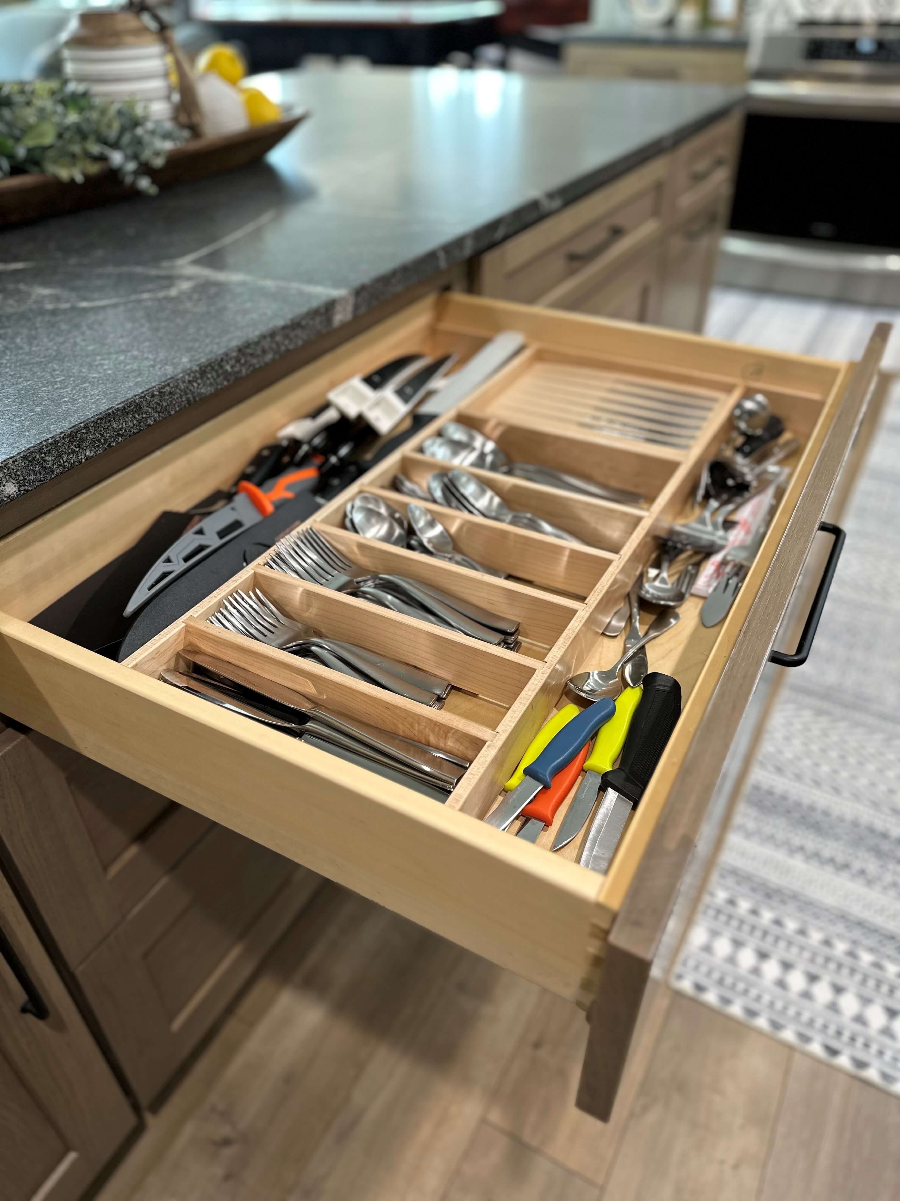 One of the top drawers in the kitchen island features a utensil organizer for storing the silverware collection as well as cutlery and extra kitchen gadgets.