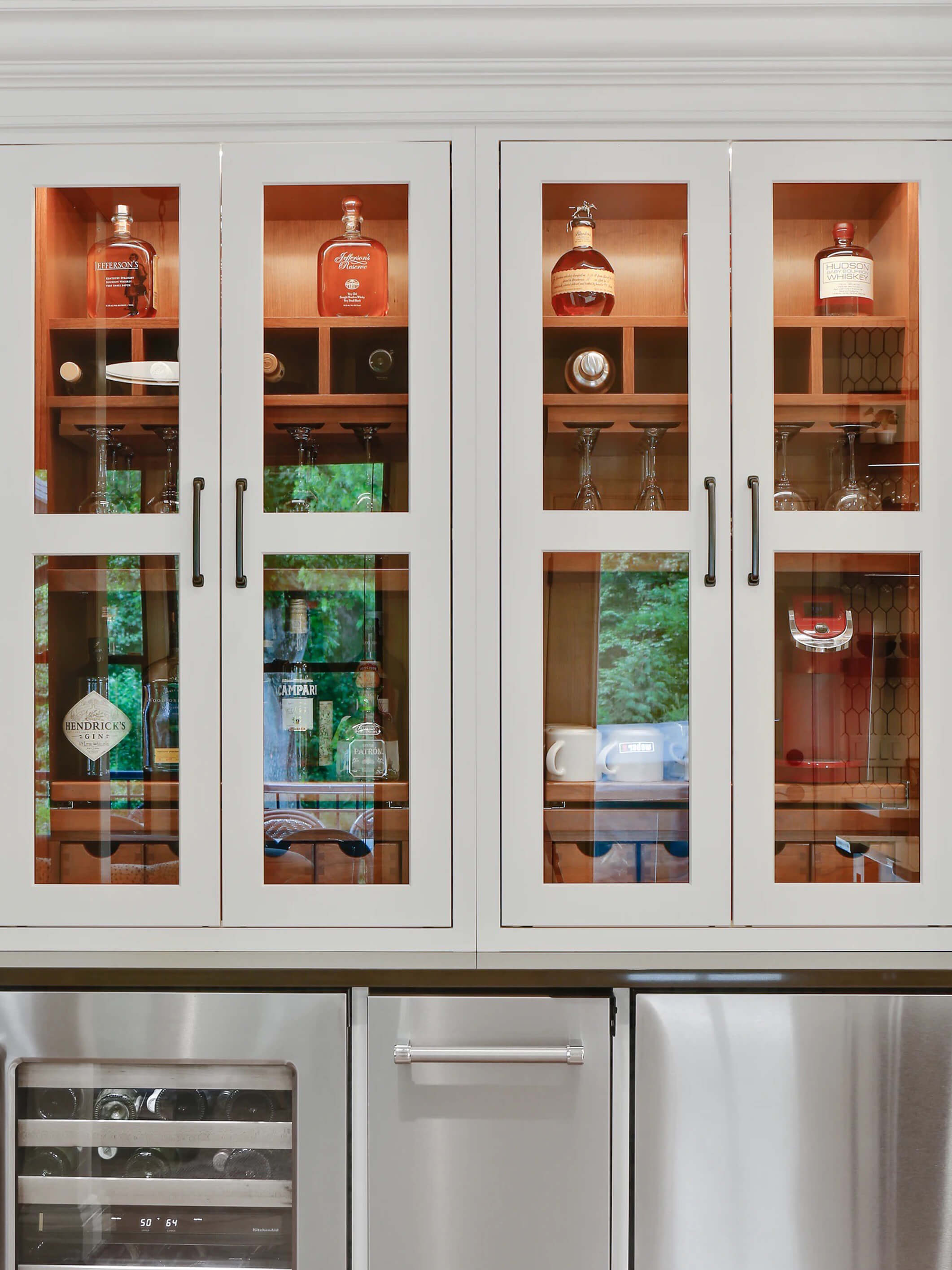 Two larder cabinets side by side with glass doors that show off the beautifully organized cabinet interiors.