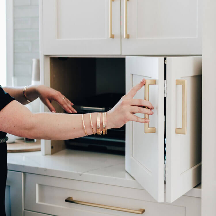 A bi-fold cabinet door that hides a small kitchen appliance on the countertop.