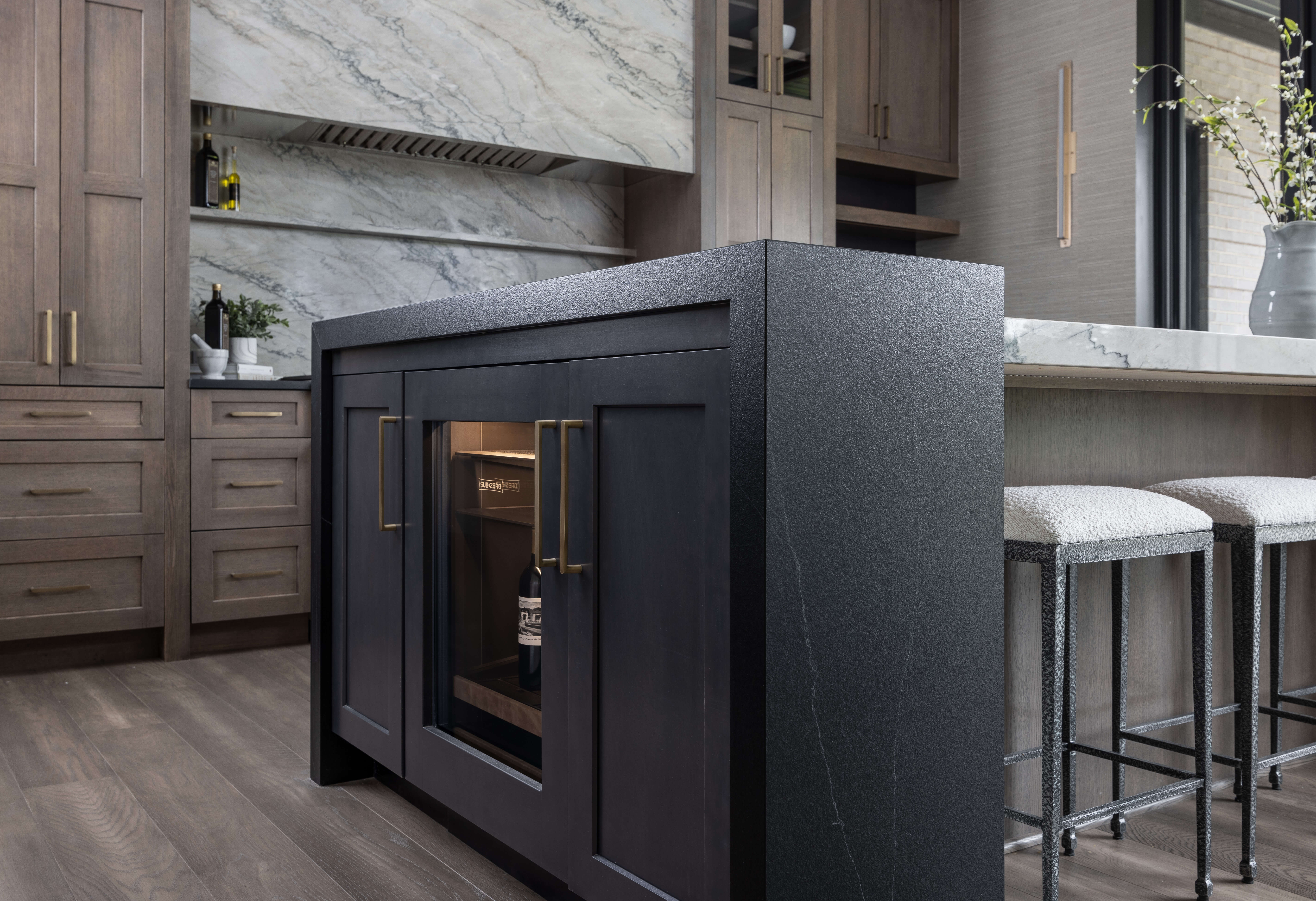 A black kitchen end cap with a beverage fridge and waterfall countertops that wrap the beverage center.