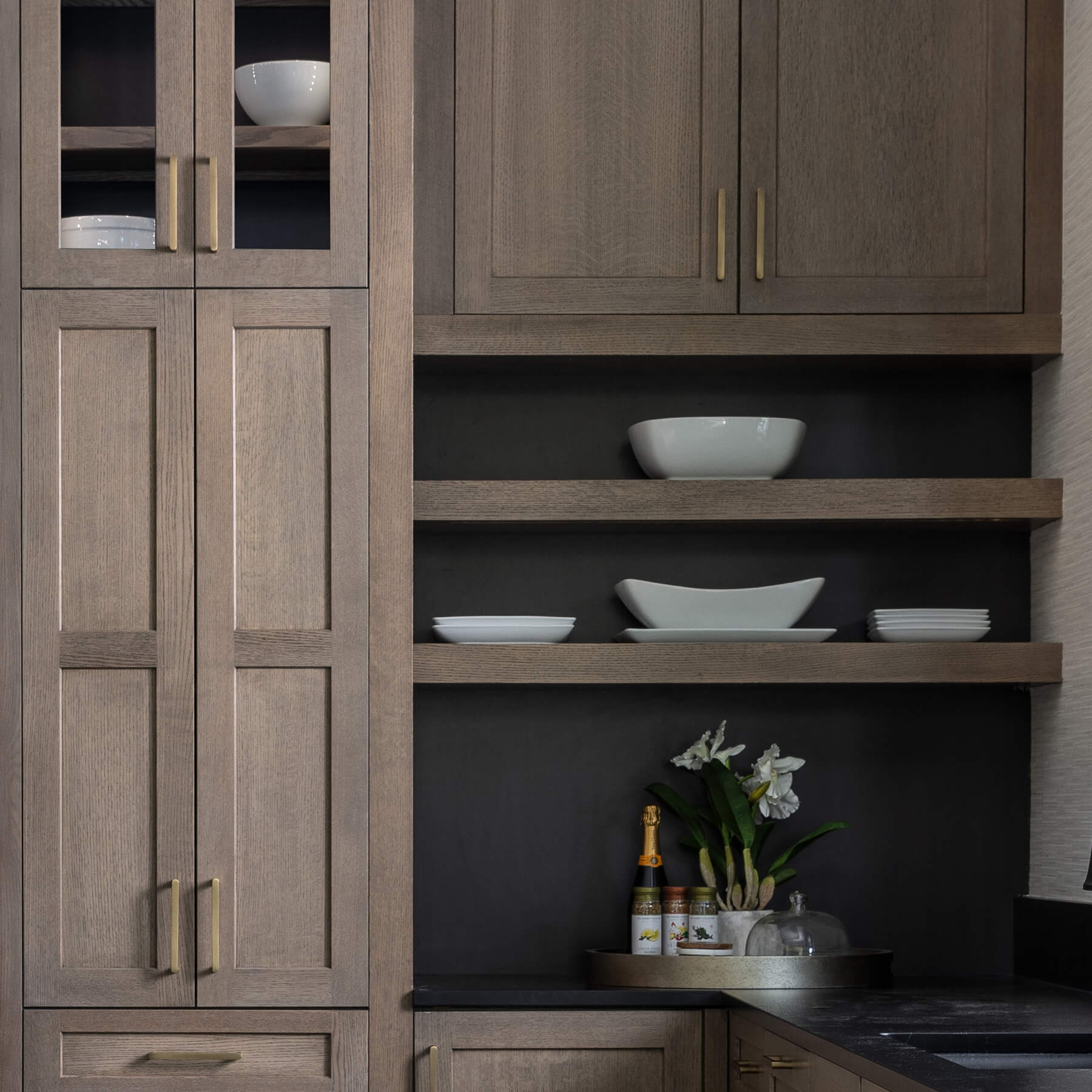 A close up of the Floating Shelves with black stain behind them and at the back of the glass door cabinets.