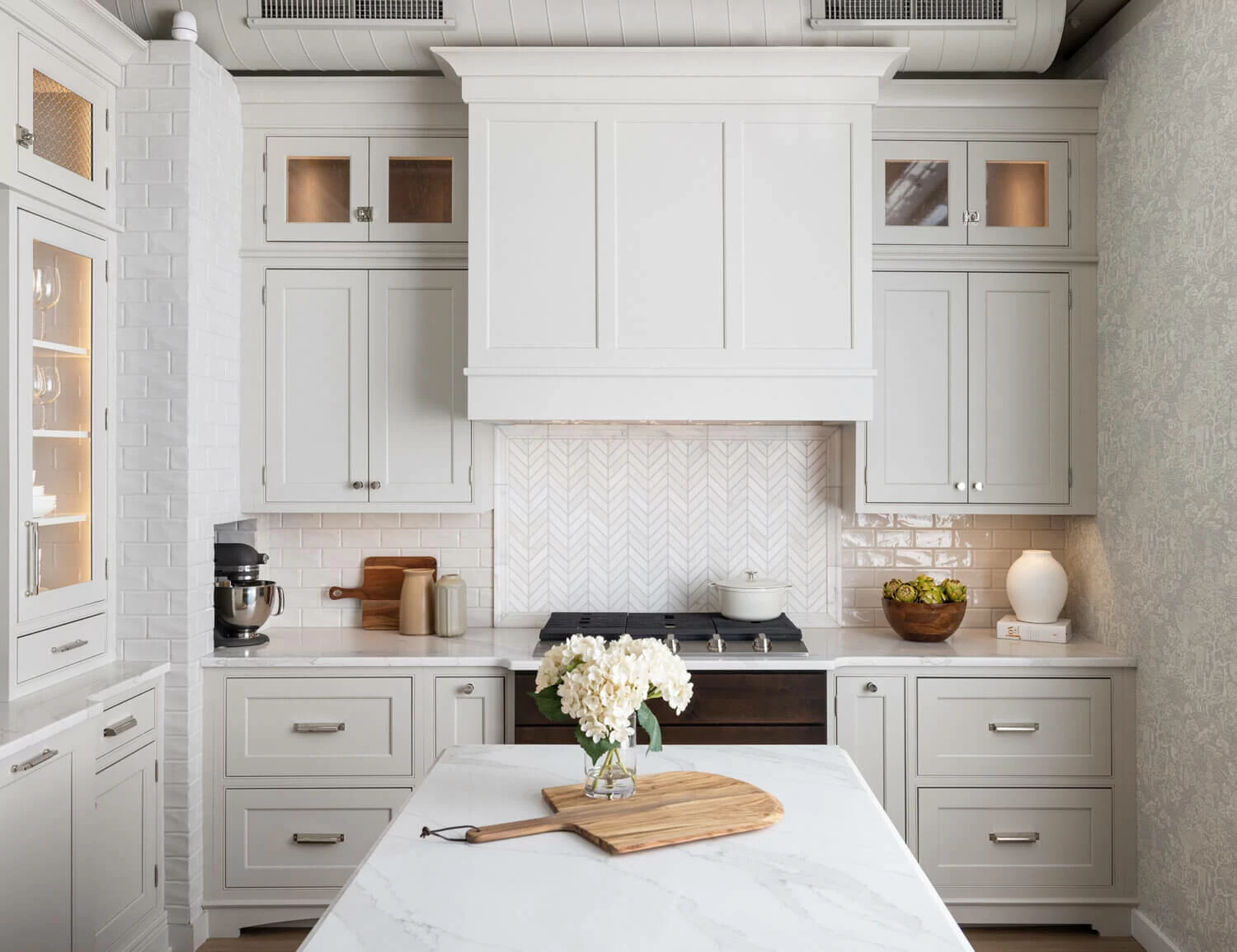 An off-white kitchen with pretty inset cabinets and a wood hood.