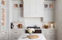An off-white kitchen with pretty inset cabinets and a wood hood.