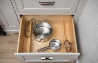 A deep drawer in a kitchen with dividers for lid storage for organizing pots & pans.