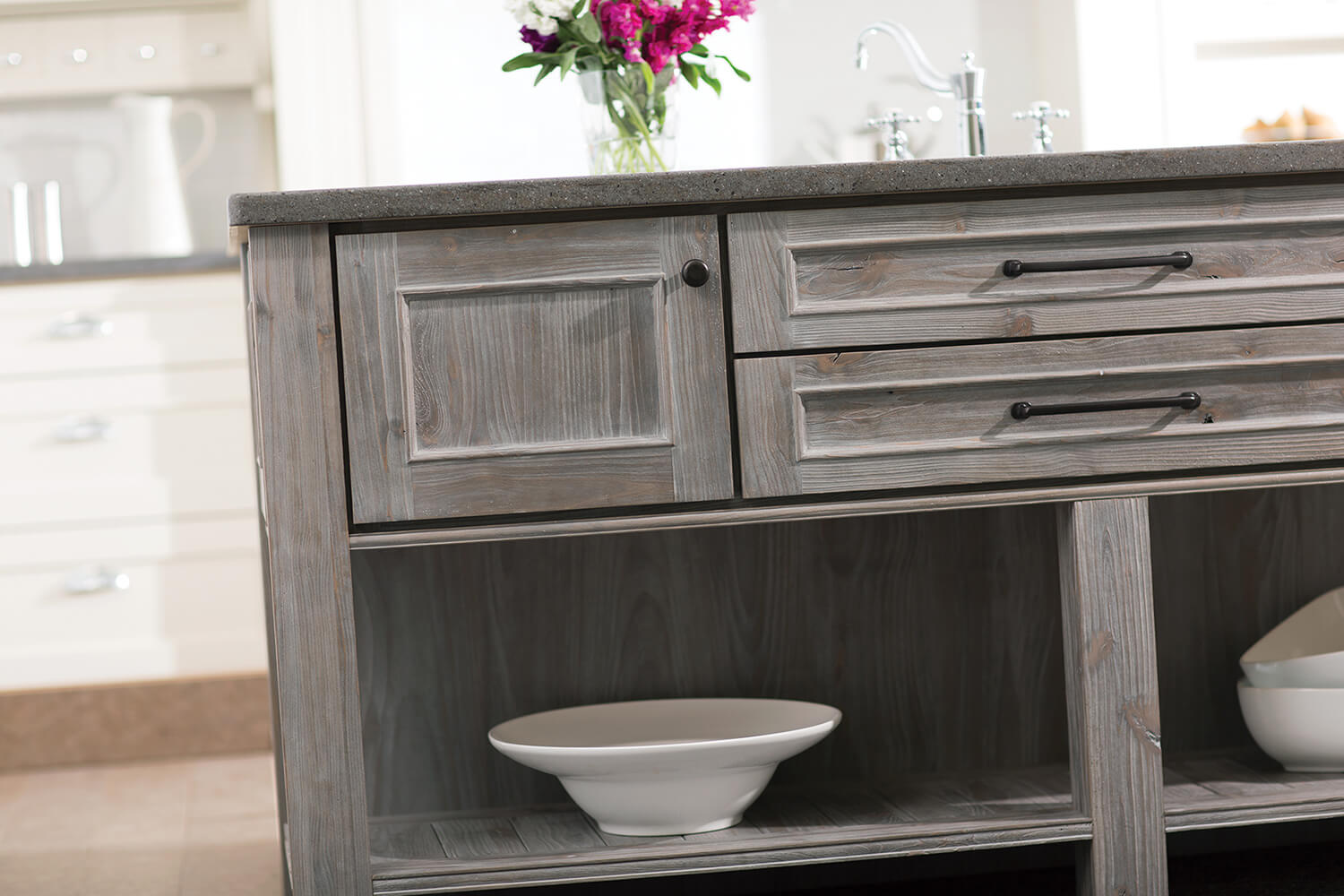 A light gray stained kitchen island with a weathered wood finish in a rustic Knotty Alder wood species.