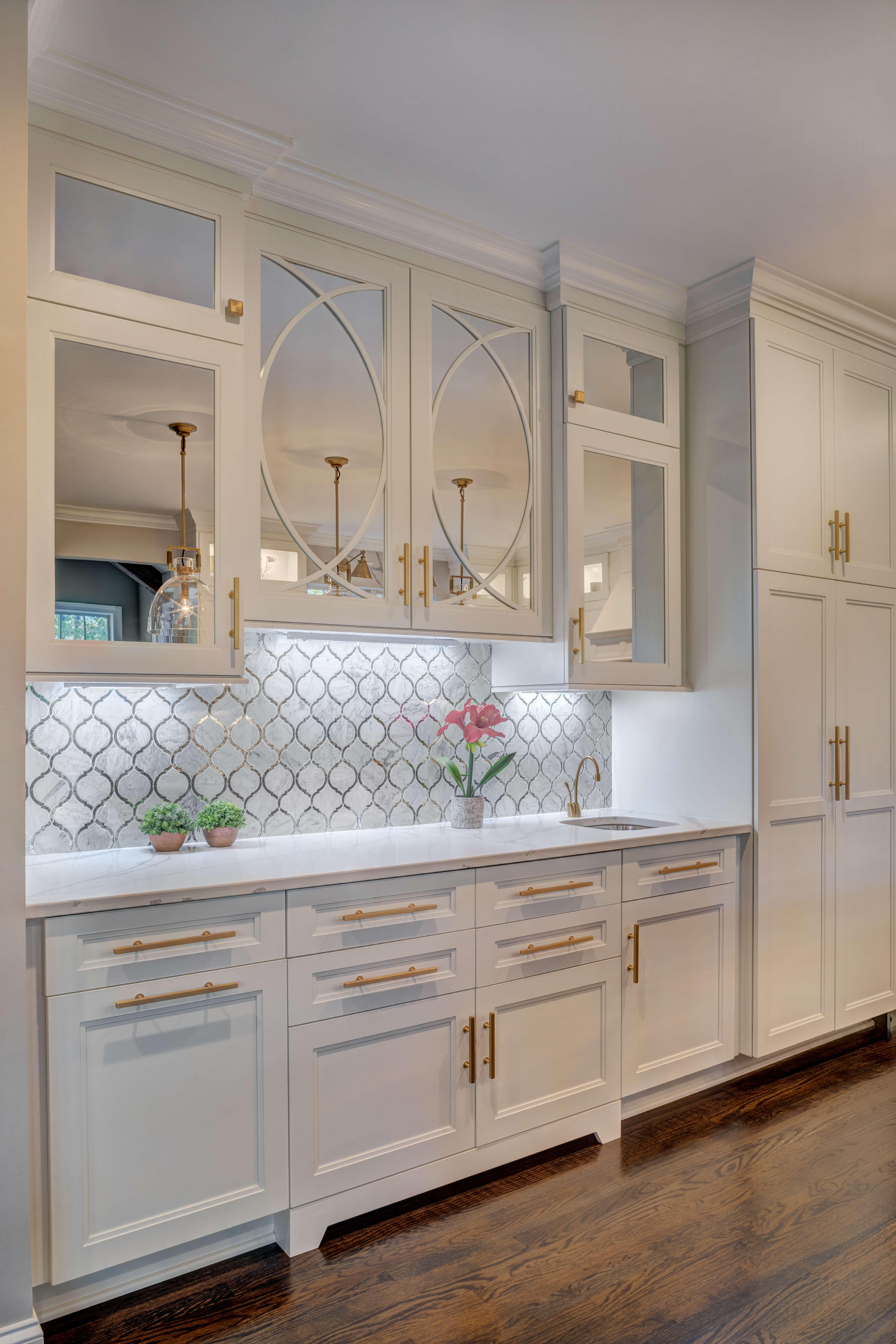 The glass cabinet doors in this white painted kitchen feature mirror inserts add an open airy feel to the space, and create the look of glass cabinets while hiding the clutter behind the cabinet doors.