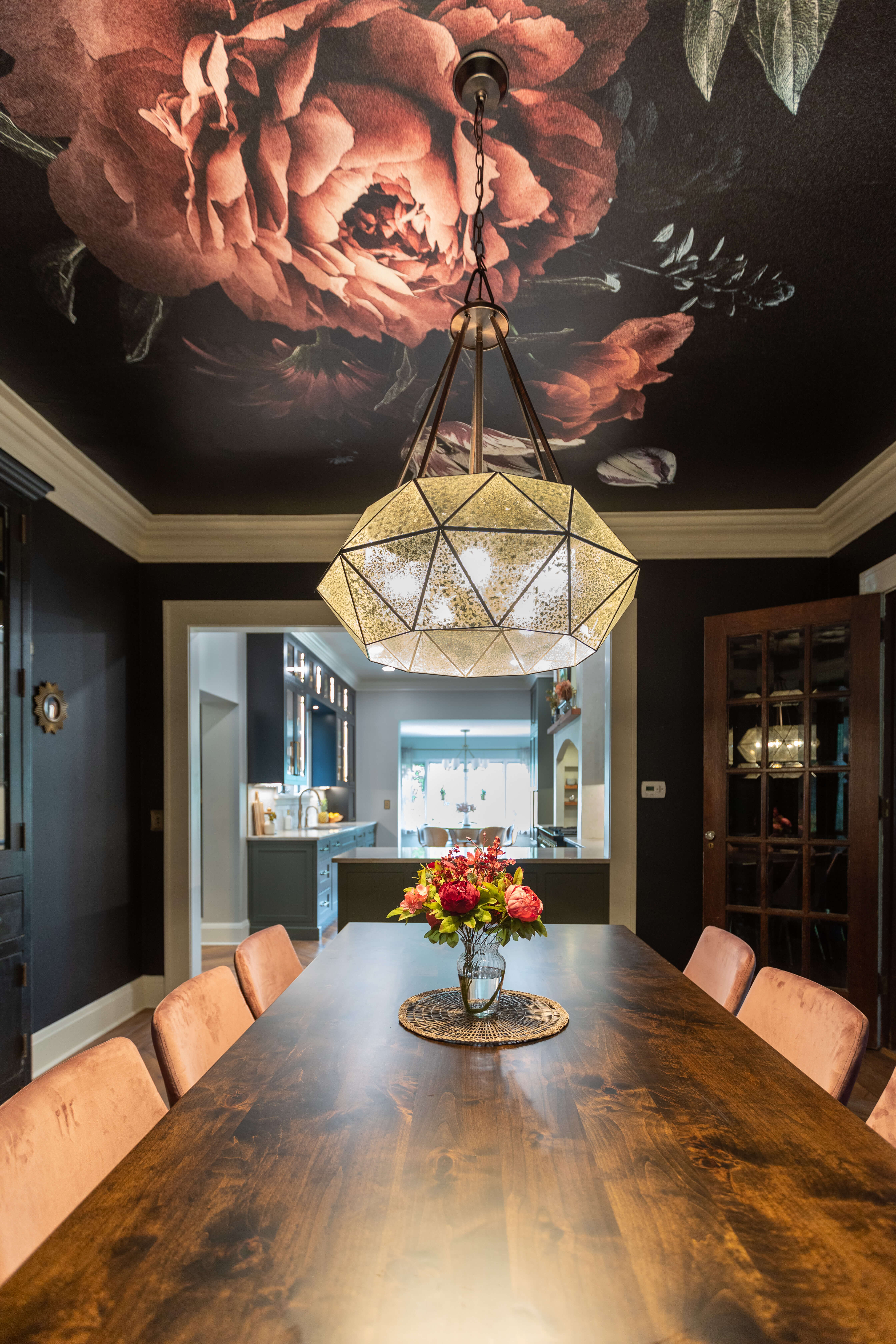 A dining room with a dramatic and bold mural painted on the ceiling of a rose.