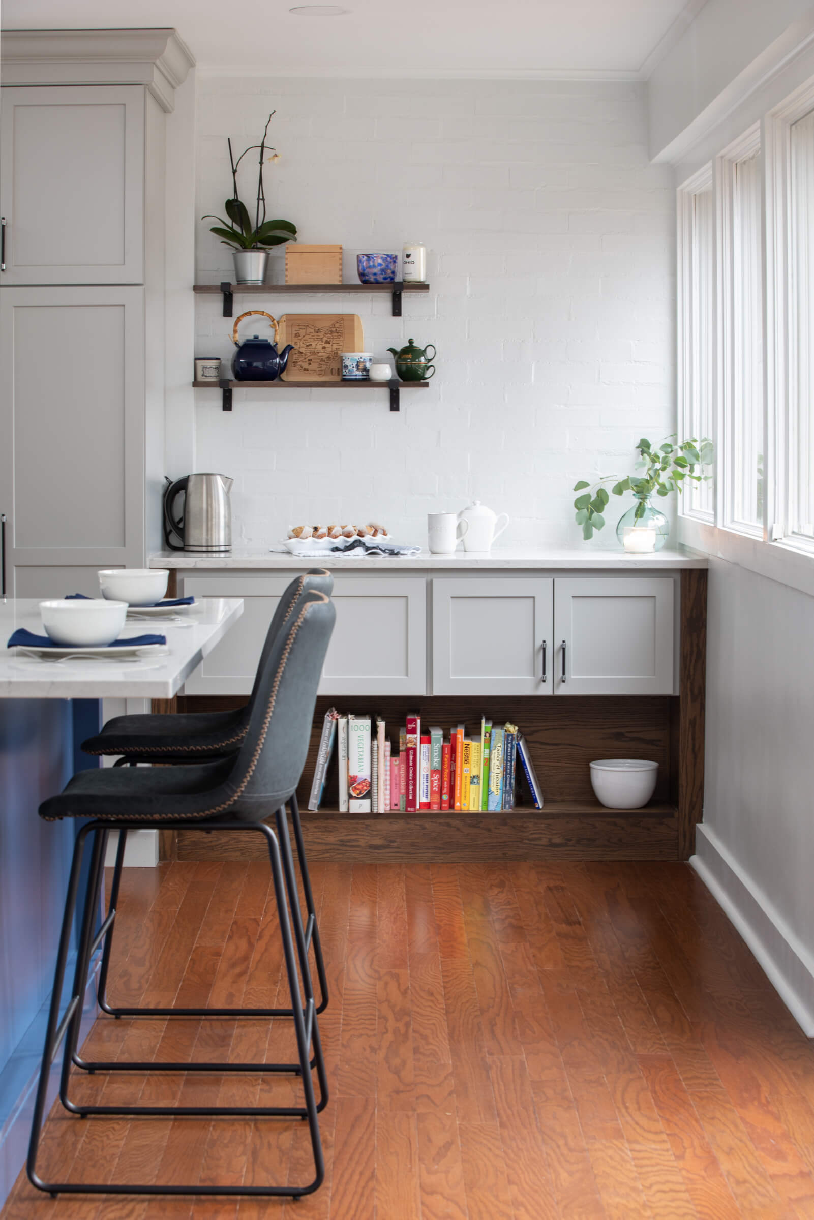 A kitchen corner that features a two-toned cabinet and open shelf space for cook books and decorative display.