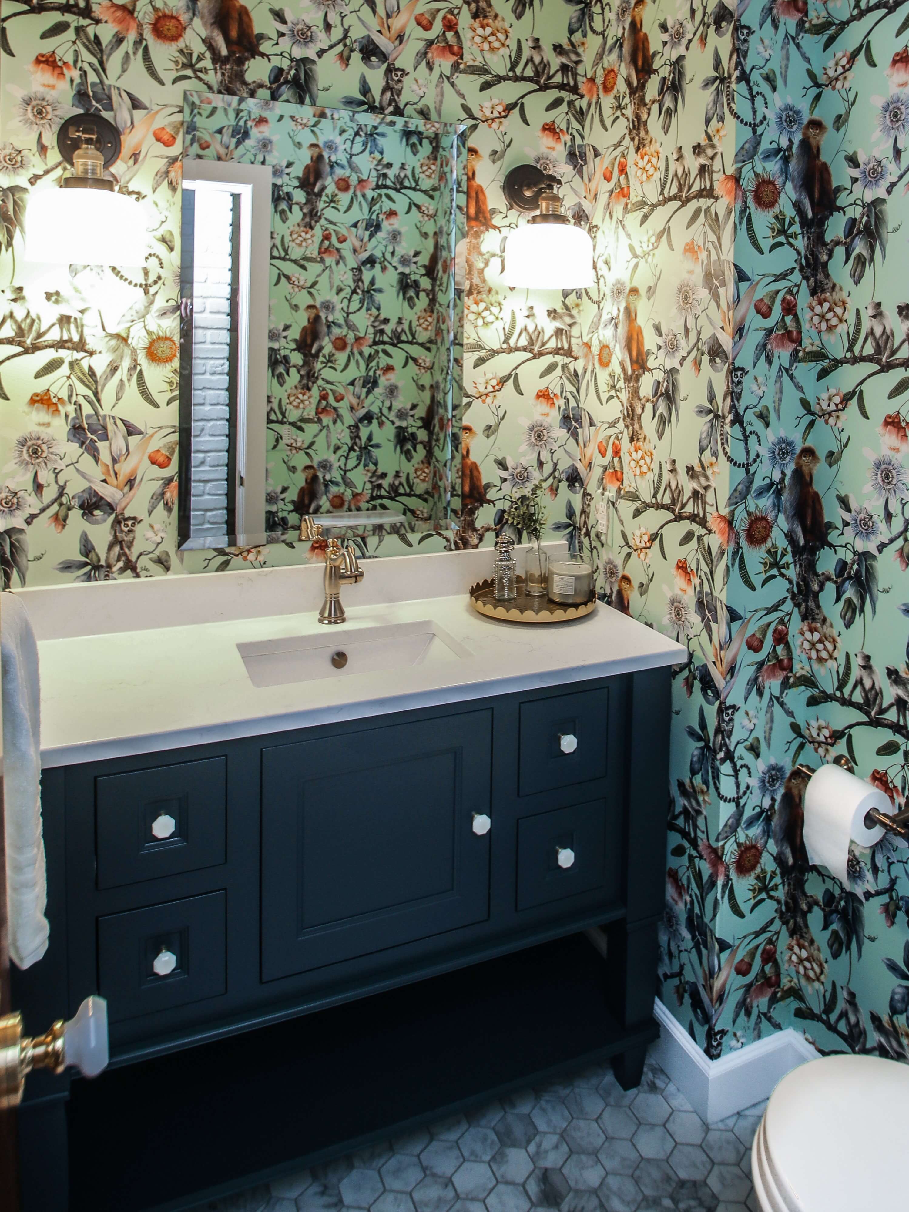 A dark navy blue furniture style vanity in a bathroom with extravagant wallpaper.