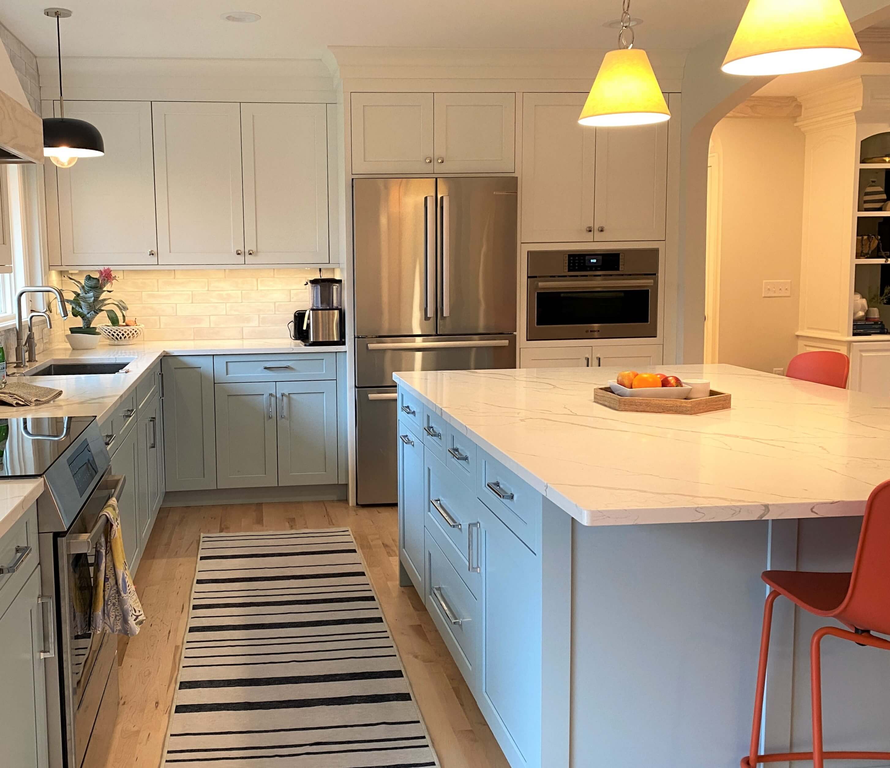 A soft contrasting kitchen with muted white painted cabinets for the wall cabinets and a delicate light blue paint color for the base cabinets and kitchen island.