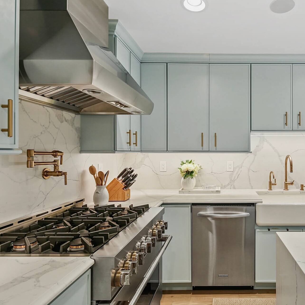 A new kitchen with modern shaker doors in a soft pale blue paint color and mixed metal finsihes.