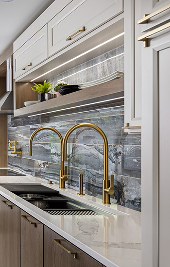 A kitchen with floating shelves and wall cabinets that have sleek, integrated under cabinet lighting.