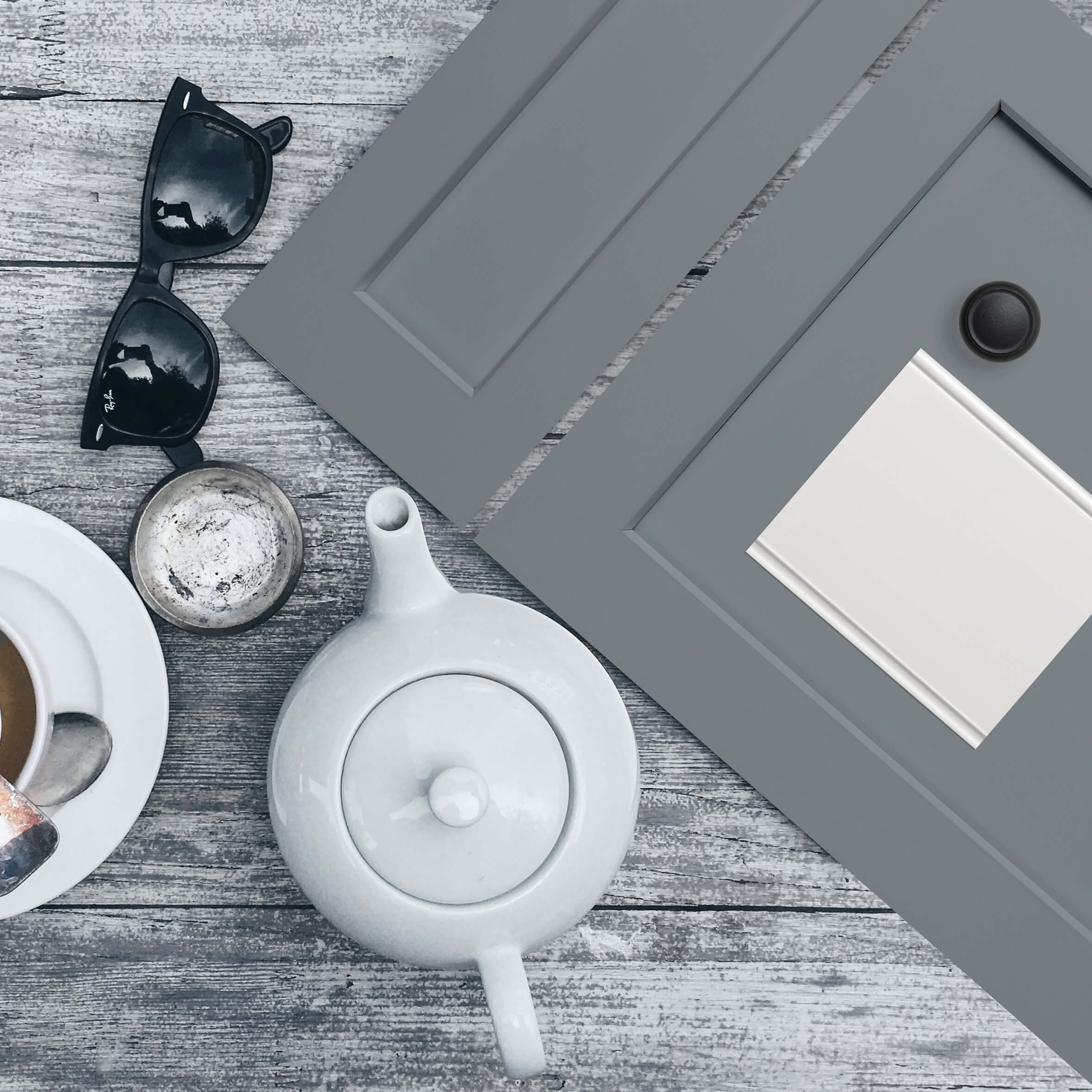 An interior design flat lay with a gray-blue painted cabinet door with a shaker, flat panel style.