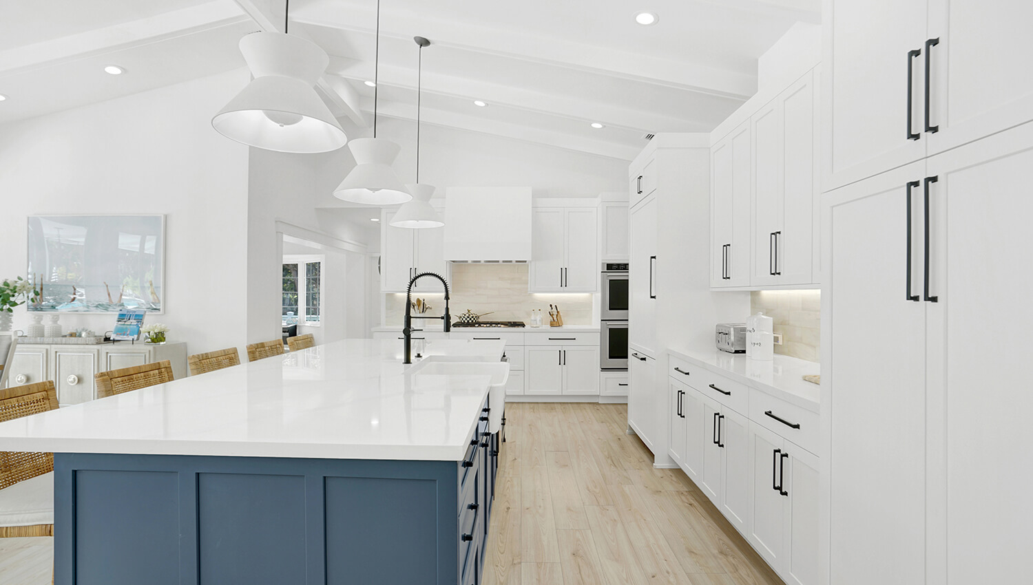 A bright white Modern Farmhouse style kitchen with a navy blue kitchen island and shaker style cabinet doors.