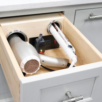 A bathroom drawer with a Vanity Grooming station with metal cups and a switch powered outlet for hair dryers and curling irons.