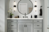 A gray painted bath vanity with reeded cabinet doors and a shallow shaker style tucked into an Arched wall with black faucet and hardware accents.