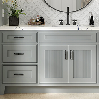 A close up of a gray vanity with reeded details on the doors.