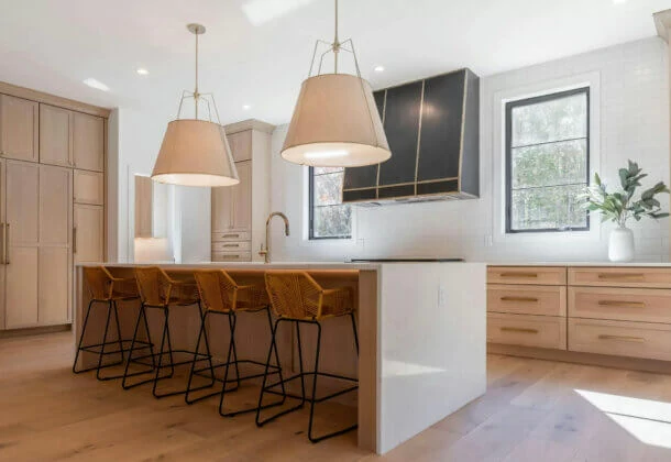 An extraordinary modern farmhouse kitchen design with qtr. sawn white oak cabinets with a light wood stain, a waterfall kitchen island and minimal wall cabinets.