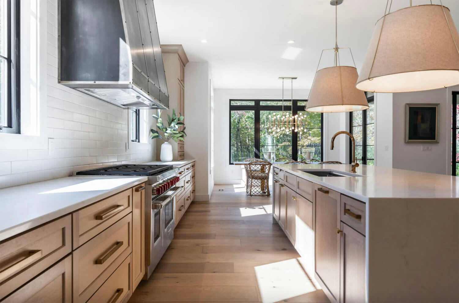 A stunning kitchen with light stained wood cabinets in White Oak with modern brassy accents and farmhouse styled pendant lights over the kitchen island.