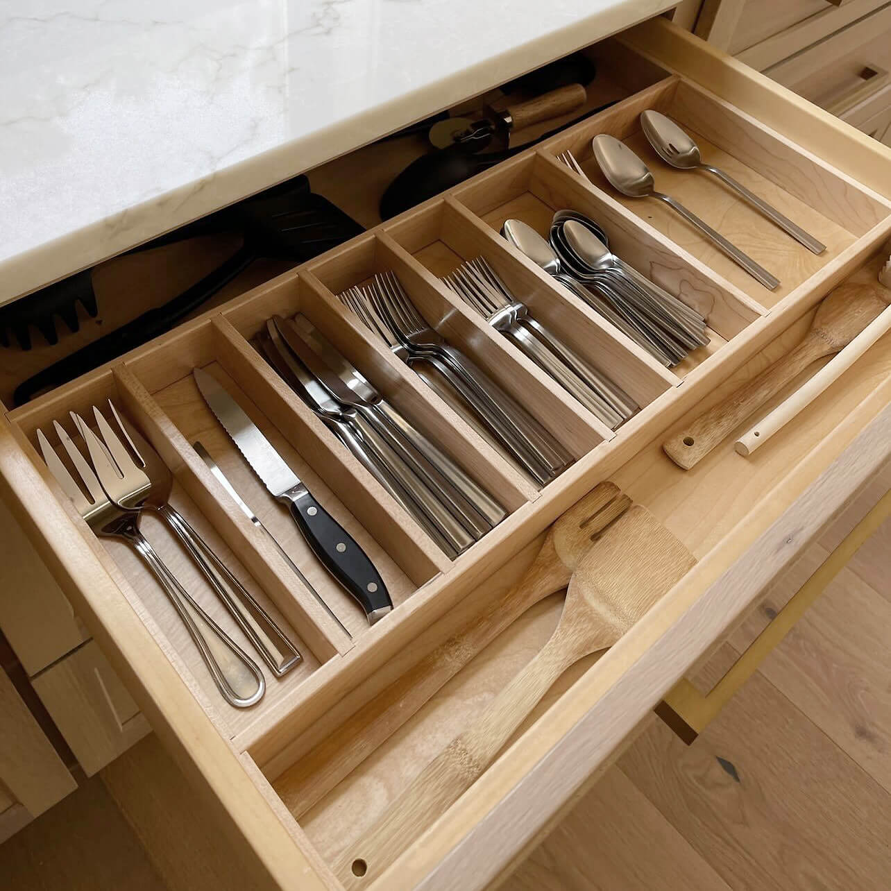 A wide kitchen drawer with organized and divided utensil and silverware storage.